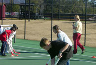 Students practicing hockey on tennis court